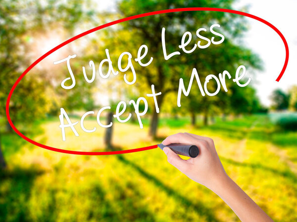 Woman Hand Writing Judge Less Accept More with a marker over tra