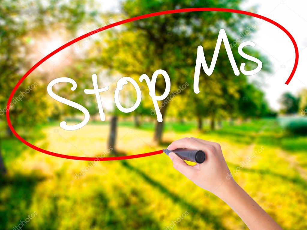 Woman Hand Writing Stop Ms with a marker over transparent board 