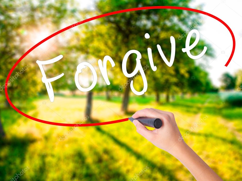 Woman Hand Writing Forgive with a marker over transparent board 