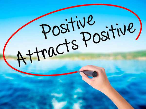 Woman Hand Writing Positive Attracts Positive with a marker over