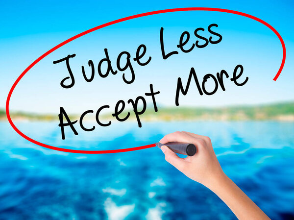 Woman Hand Writing Judge Less Accept More with a marker over tra