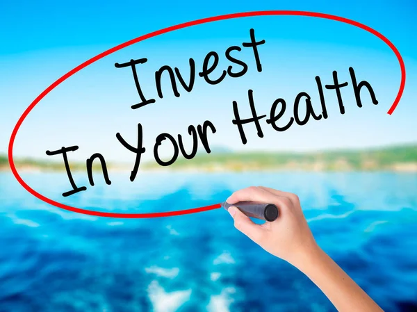 Woman Hand Writing Invest In Your Health with a marker over tran