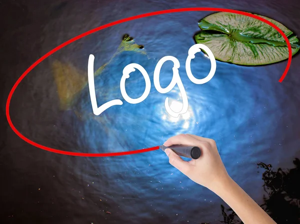 Mulher mão escrita logotipo com marcador sobre placa transparente — Fotografia de Stock