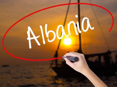 Woman Hand Writing Albania  with a marker over transparent board clipart