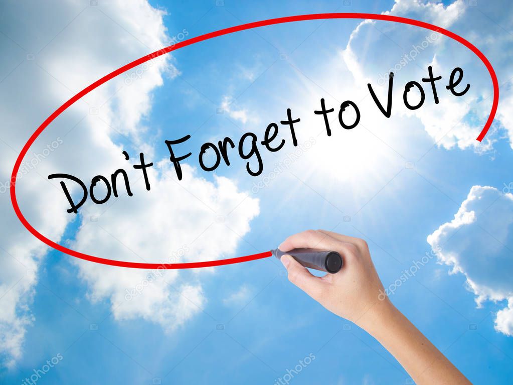 Woman Hand Writing Don't Forget to Vote with black marker on vis