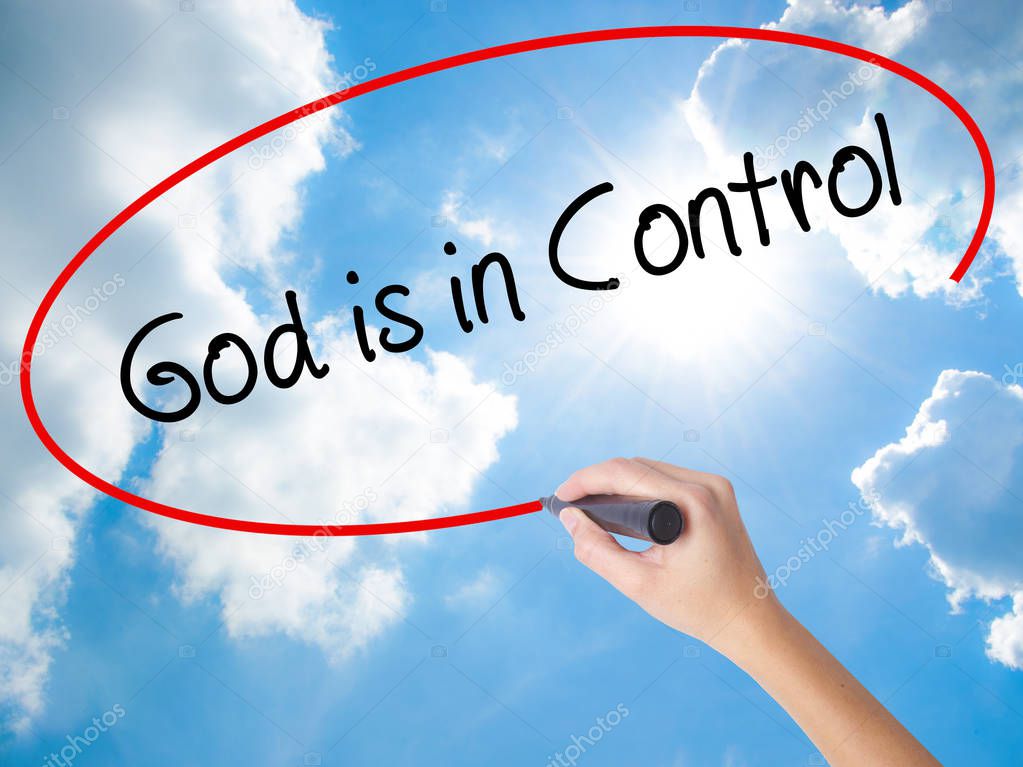 Woman Hand Writing God is in Control with black marker on visual