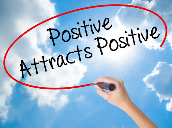 Woman Hand Writing Positive Attracts Positive with black marker 