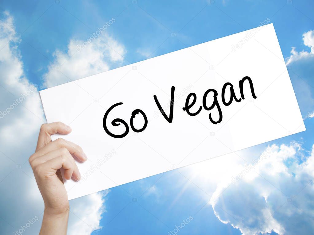 Go Vegan Sign on white paper. Man Hand Holding Paper with text. 