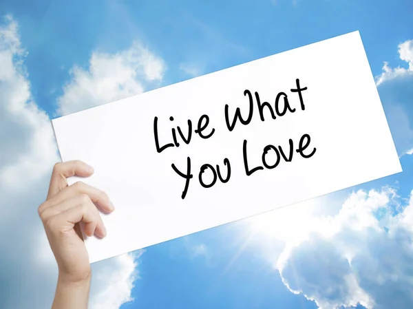 Live What You Love  Sign on white paper. Man Hand Holding Paper
