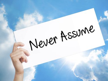 Never Assume Sign on white paper. Man Hand Holding Paper with te clipart