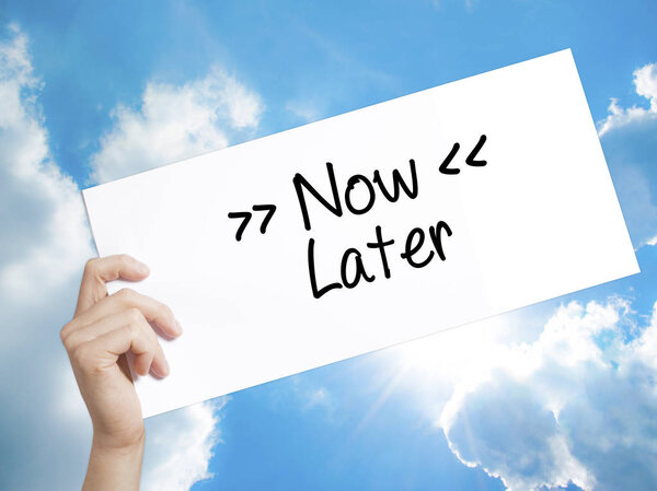 Now / Later Sign on white paper. Человек, держащий бумагу с текстом
.