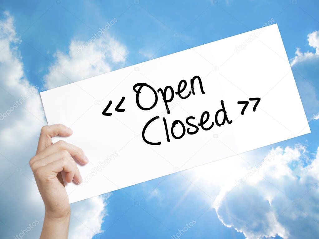 Open - Closed Sign on white paper. Man Hand Holding Paper with t