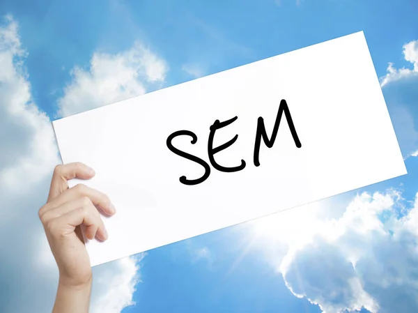 SEM (Search Engine Marketing) Sign on white paper. Man Hand Hol
