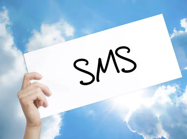 SMS (Short Message Service) teken op wit papier. Man Hand vasthouden — Stockfoto