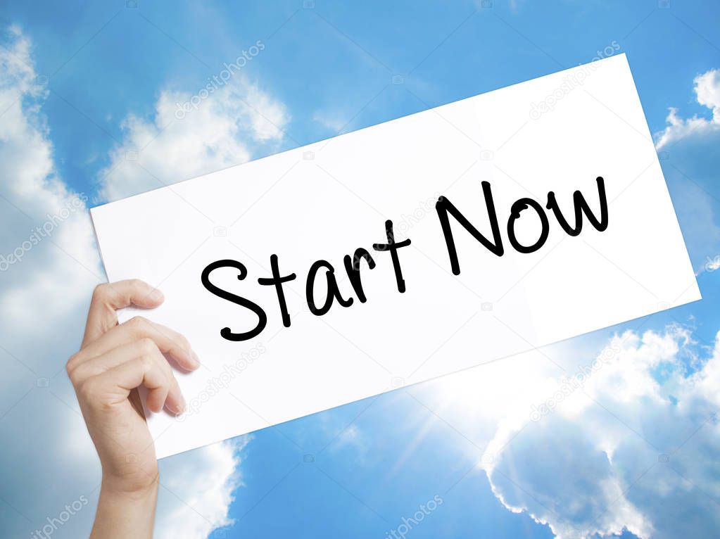 Start Now Sign on white paper. Man Hand Holding Paper with text.