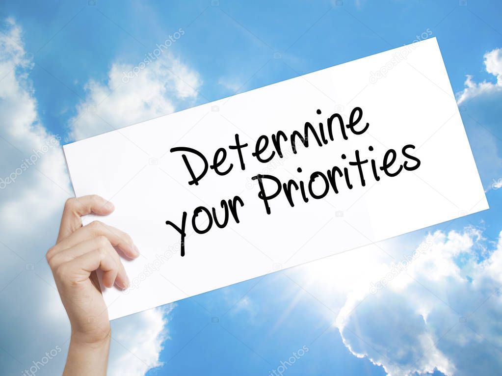 Determine your Priorities Sign on white paper. Man Hand Holding 
