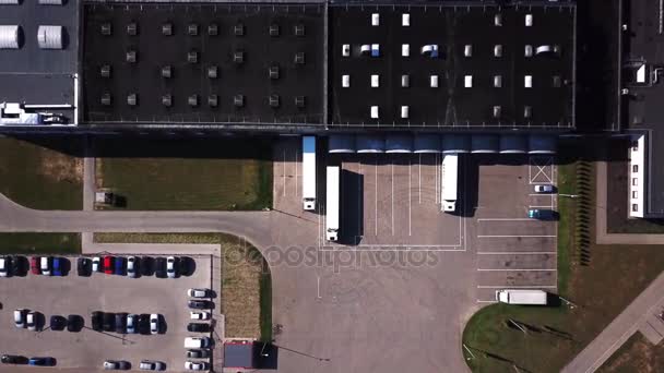 Zoom z letecký záběr z průmyslového skladu / skladovací budova / načtení oblast, kde jsou načítání mnoho nákladních vozidel / vykládka zboží. — Stock video