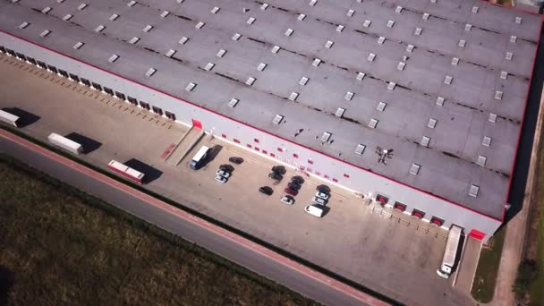 Zoom arrière Vue aérienne de l'entrepôt industriel / bâtiment de stockage / zone de chargement où de nombreux camions chargent / déchargent des marchandises . — Video