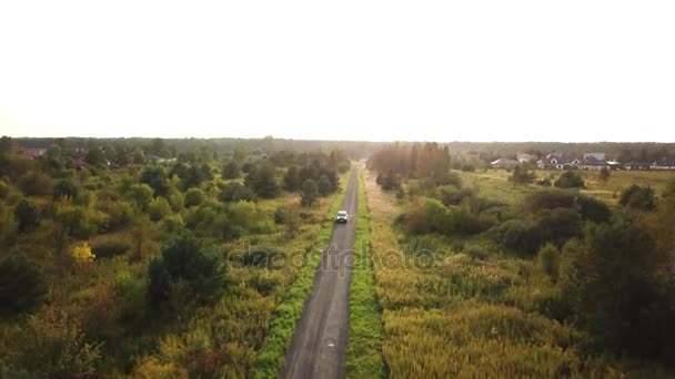 Black SUV car driving along empty country highway in idyllic rural landscape. People on road trip journey across beautiful green — Stock Video
