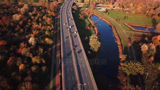 4k luchtfoto: auto's en semi vrachtwagen rijden op drukke snelweg in het hele land in mooie herfst avond. Mensen op road trip reizen op drukke snelweg op gouden zonsondergang — Stockvideo