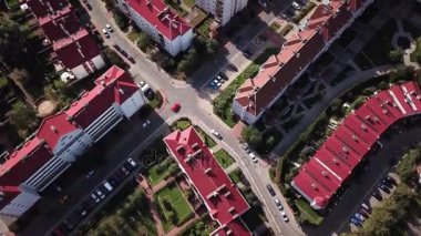Hava yukarıdan aşağı mahalle evleri kırmızı çatılar ile de park etmiş arabaların gösteren ve daha fazla evleri 4 k doğru yol geçiş üzerinde uçan bir şehir üzerinde uçan görünümü. Aşağıdaki kırmızı arabalar