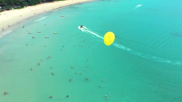 Diversão de água parasitária. Voando em um paraquedas atrás de um barco em umas férias de verão pelo mar no resort. Bela água azul brilhante e paraquedas vermelho e branco . — Vídeo de Stock