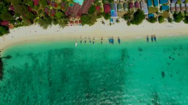 Denizde uzun kuyruklu teknenin havadan görünüşü, yukarıdan görüntü. Turkuaz mavi ve yeşil deniz suyunda yüzen uzun kuyruklu teknenin hava videosu. Tropikal manzara Phi Adası, Andaman Denizi, Krabi, Tayland