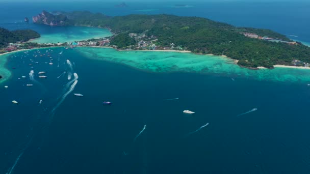 Turkoois helder water. Jachten, drijvende boten. Waterverloop van licht naar donkerblauw. Phi Phi don Island, schietend vanuit een drone vanuit de lucht. Wit zand, groene bomen, palmbomen en grote heuvels. — Stockvideo