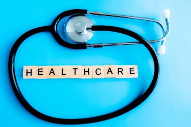 Sağlık hizmeti konsepti. Stetoskop, mavi arkaplan arkaplan görünümlü fotokopi alanına yakın. Ahşap harfler Sağlık Hizmetleri.