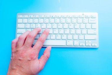 Evde bilgisayarcıyla blog yazarken. Adam elleri klavyede.