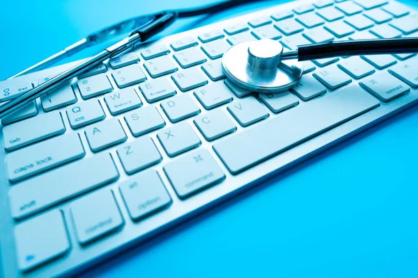 Healthcare and medicine or computer antivirus protection and repair maintenance service concept: macro view of blue stethoscope on business office laptop notebook keyboard with selective focus effect