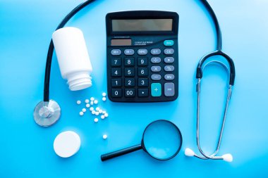 İlaç ve haplar büyüteç altında tıbbi bir steteskopun yanında. Sağlık konsepti ve ilaçların, vitaminlerin ve çeşitli takviyelerin sorumlu kullanımı