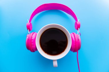 Mavi arka planda kulaklık ve kahve fincanı. Müzik konsepti. Kopyalama alanı olan üst görünüm
