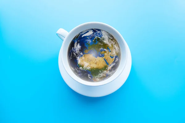 A cup of coffee with a shape of World. Blue background