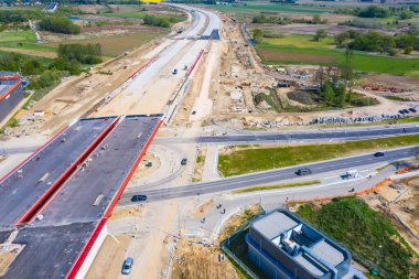 Havadan aşağıya, bitmemiş asfalt yol manzaralı, inşaat alanında ağır makineler var. Hiçliğe giden yol.