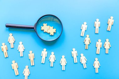 Mavi arka planda insanların simgesi olan büyüteç imajı, güçlü bir ekip kurmak, insan kaynakları ve yönetim kavramı. Bulmacalar