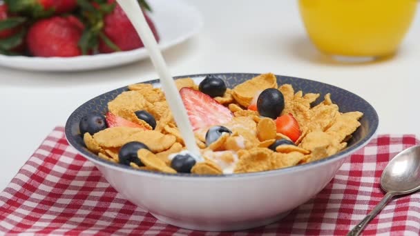 Утренний завтрак Молоко, льющееся в миску с кукурузными хлопьями и ягодами — стоковое видео