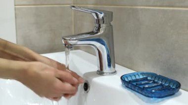 Koronavirüs salgınını önlemek için ellerini çorbayla yıkayan kadın.
