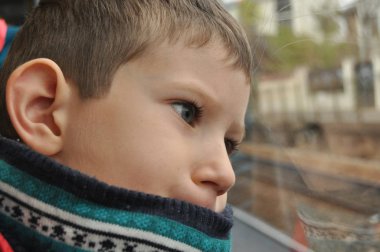 Çocuk pencerenin altından şehri izliyor.