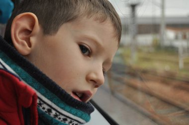 Çocuk pencerenin altından şehri izliyor.