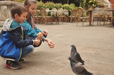 Venedik, bir yaya Caddesi üzerinde çocuklar tarafından ekmek kırıntısı beslenen güvercinler.