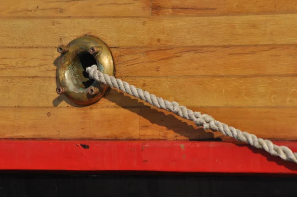 Σχοινί πρόσδεσης βγαίνει από την τρύπα στην πλευρά του πλοίου. Χοντρά σχοινιά. — Φωτογραφία Αρχείου