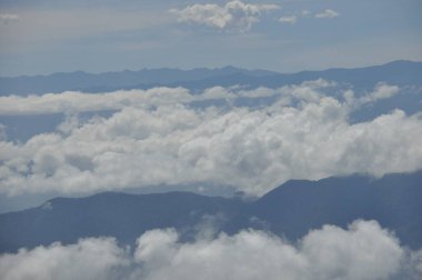 Kosta Rika 'daki Irazu volkanının tarım yamaçlarında verimli topraklar ve güneşli yamaçlarda sayısız mahsul var. Vadi volkanik koninin altında asılı bulutlarla çevrilidir..