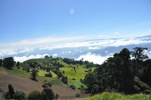 コスタリカの火山イラズの農業斜面肥沃な土壌と日当たりの良い斜面に多数の作物 谷は火山錐の下に浮遊する雲に囲まれている — ストック写真