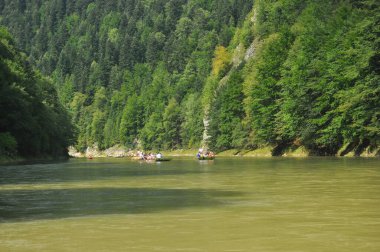 Pieniny Ulusal Parkı 'ndaki Dunajec Nehri' nde rafting yaparken ahşap katlanır mekiklerin üzerinde iple bağlanmıştı. Rafterler akıntıya karşı kürek çekiyor, dibi kayalık ve akıntısı güçlü..