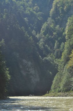 Pieniny Ulusal Parkı 'ndaki Dunajec Nehri' nde rafting yaparken ahşap katlanır mekiklerin üzerinde iple bağlanmıştı. Rafterler akıntıya karşı kürek çekiyor, dibi kayalık ve akıntısı güçlü..