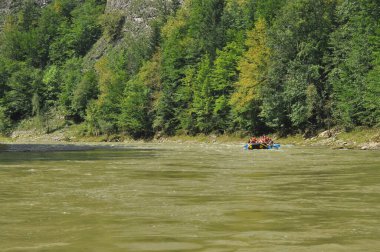 Pieniny Ulusal Parkı 'ndaki Dunajec Nehri' nde rafting yaparken ahşap katlanır mekiklerin üzerinde iple bağlanmıştı. Rafterler akıntıya karşı kürek çekiyor, dibi kayalık ve akıntısı güçlü..