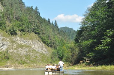 Pieniny Ulusal Parkı 'ndaki Dunajec Nehri' nde rafting yaparken ahşap katlanır mekiklerin üzerinde iple bağlanmıştı. Rafterler akıntıya karşı kürek çekiyor, dibi kayalık ve akıntısı güçlü..