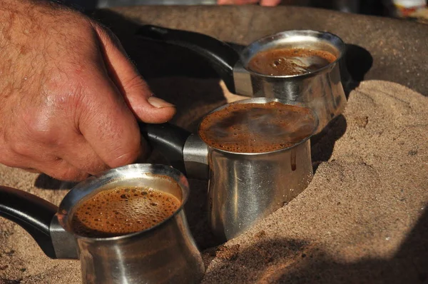 Arabic coffee brewed in a brass metal crucible in hot sand on one of the street stalls in Aqaba, Jordan. Aroma of coffee with cardamom and sugar for 1 Jordanian dinar.