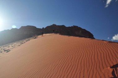 Ürdün 'deki Wadi Ram çölünde yüksek, kumlu bir kumuldan inen çocuklar. Uzak bir ülkeye seyahat ederken çok eğlenceli..